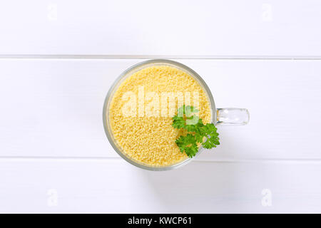 Schale der rohen Couscous auf weißem Holz- Hintergrund Stockfoto