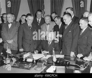 Präsident Harry Truman unterzeichnet Gesetz zur Gründung der oberen Colorado River Basin Kompakt. April 6, 1949. Vier Männer hinter Truman's Chair, L-R: Innenraum Sec. Julius Krug (gestreifte Krawatte); Sen. Lester Jagd ; Senator Clinton Anderson; Sen. Dennis Chavez (Holding Zigarre). - (BSLOC 2014 15 78) Stockfoto