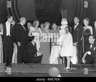 Bess und Margaret Truman am Roosevelt Geburtstag Ball mit Hollywood Berühmtheiten. First Lady Bess Truman und ihre Tochter Schneide den Kuchen an der Roosevelt Geburtstag Ball Spendenaktion 1946 für den März der Groschen "Kampf gegen die Kinderlähmung. Feiert gehören: Margaret O'Brien (vor Kuchen); Charles Coburn (zweite von links); Gene Kelly (kniend links); Paul Henreid (dritter von rechts);, Cesar Romero (kniend, rechts; Alexis Smith (Zweiter von rechts). - (BSLOC 2014 15 93) Stockfoto