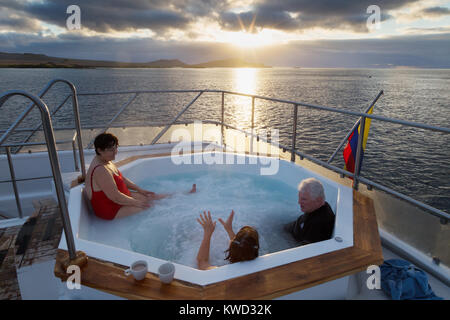 Galapagos Reisen - Touristen in einem Whirlpool auf dem Kreuzfahrtschiff beobachten Sonnenuntergang über der Insel Floreana, Galapagos, Ecuador Südamerika Stockfoto