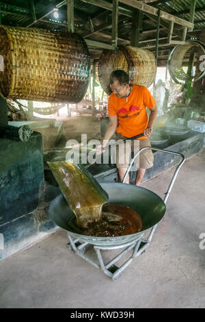 Thailändische Arbeiter entfernen verdampft Kokosnuss Zucker sap-Sirup von heißen Pfannen bei Kokosnuss Zucker Plantation, Tambon Kradangnga, Samut Songkhram, Thailand. Stockfoto