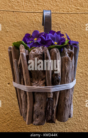 Haus und Straße Dekorationen: Eine hölzerne Blumentopf von stiefmütterchen hängen von einem Bügeleisen Seil Stockfoto