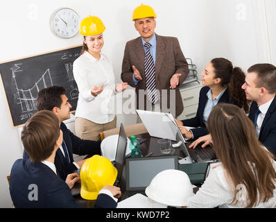 Gruppe erwachsener Ingenieure diskutieren neues Projekt und lächelnd im Innenbereich Stockfoto