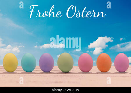 Bunte Ostereier auf einem Holzbrett mit der Frohe Ostern Schrift Stockfoto