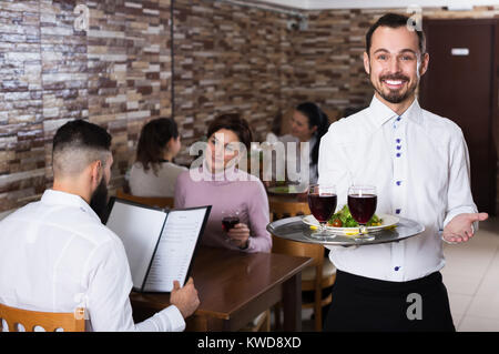 Positive männliche Kellner mit rustikalen Restaurant für Besucher Stockfoto