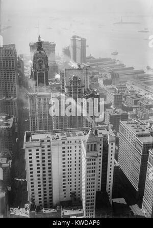 Gebogene Spitze der Sänger Turm aus das Woolworth Building in Downtown Manhattan, C. 1920. Singer Tower ist ein 47-stöckiges Bürogebäude und war das höchste in der Welt von 1908 bis 1909. Hafen von New York und die Freiheitsstatue sind in der Ferne (BSLOC 2016 10 200) Stockfoto