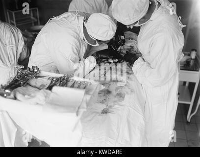 Die Teilnahme an Chirurgen lehnt sich eng über Abdomen des Patienten zu arbeiten. Das OP-Feld ist mit Blut befleckt. 1922 in einem Krankenhaus in Washington, D.C. (BSLOC 2016 10 36) Stockfoto