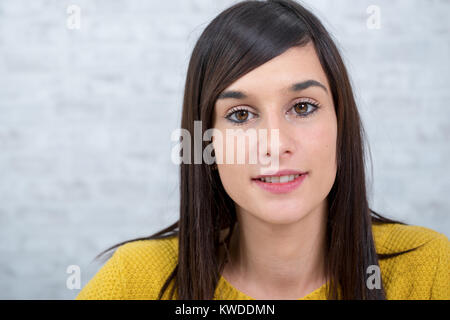 Eine junge Brünette und lächelnde Frau in Gelb gekleidet Stockfoto