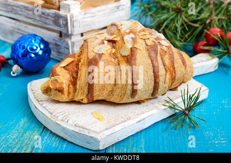 Croissants mit mandelflocken auf einem blauen Hintergrund aus Holz. Frühstück. Traditionelles französisches Gebäck. Stockfoto