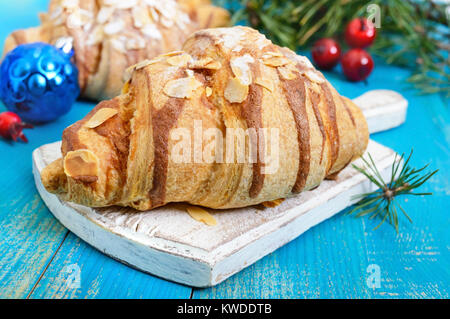 Croissants mit mandelflocken auf einem blauen Hintergrund aus Holz. Frühstück. Traditionelles französisches Gebäck. Stockfoto