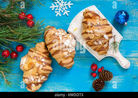 Croissants mit mandelflocken auf einem blauen Hintergrund aus Holz. Frühstück. Traditionelles französisches Gebäck. Stockfoto