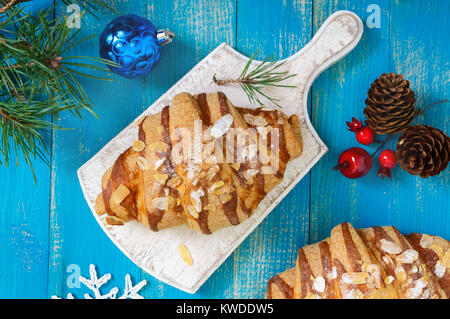 Croissants mit mandelflocken auf einem blauen Hintergrund aus Holz. Frühstück. Traditionelles französisches Gebäck. Stockfoto