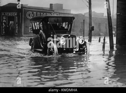 Ein Automobil fährt durch Axel hoch Wasser auf einem überfluteten Cleveland Street, wahrscheinlich im Jahr 1913. Die frühe Autos wurden mit hohen Abstände die rauen Straßen der Zeit zu navigieren. Die grosse Flut von 1913 war Ohios größte Wetter Katastrophe des frühen 20. Jahrhunderts (BSLOC 2017 17 95) Stockfoto