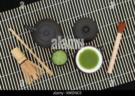 Grüner japanischer Matcha Tee mit Pulver und Drink in eine Schale mit Schneebesen, Bürste und Schaufel auf Bambus Hintergrund. Gesundheit Getränk Konzept. Stockfoto