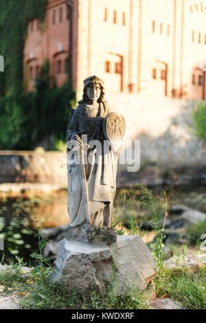 Steinerne Statue mit Schwert und Schild auf einem Stein. Stockfoto