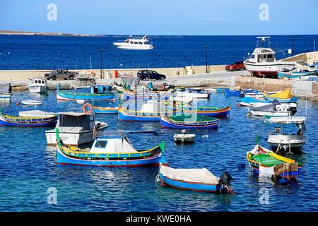 Traditionelle maltesische Dghajsa Fischerboote im Hafen mit Blick auf die Küste, San Pawl, Malta, Europa. Stockfoto