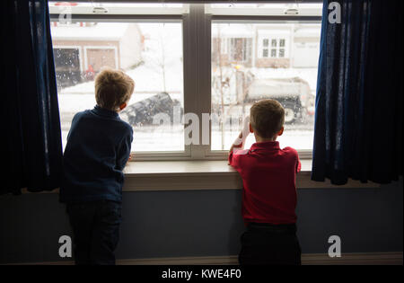 Ansicht der Rückseite des Brüder Blick durch Fenster, während zu Hause stehend Stockfoto