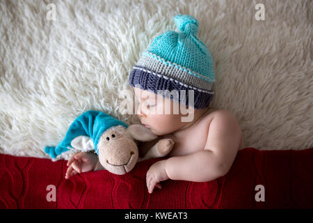 Wenig schlafen neugeborene baby boy, tragen Strickmütze, Spielzeug Stockfoto