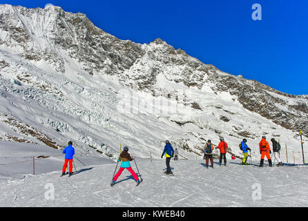 Skifahrer auf dem Weg zur Längfluh Skigebiet, Gebühr Gletscher und das Mischabel massiv hinter, Skigebiet Saas-Fee, Wallis, Schweiz Stockfoto