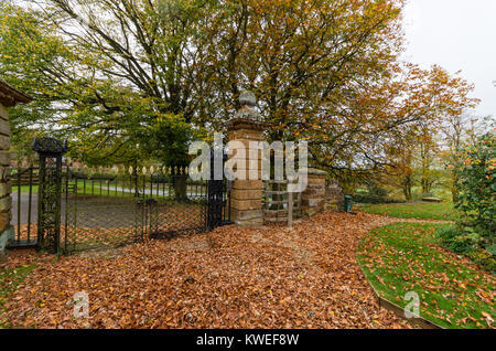 Stapel der Blätter im Herbst sammeln sich vor den Toren der Kirche St. Maria, Great Brington, Northamptonshire, England, Großbritannien Stockfoto