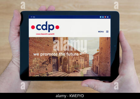 Ein Mann schaut auf die CDP-Bank (Cassa Depositi e Prestiti) Website auf seinem iPad tablet device, auf einer hölzernen Tischplatte Hintergrund (nur redaktionelle Nutzung) Stockfoto