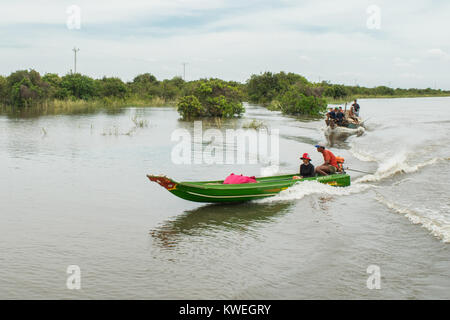 Ein KAMBODSCHANISCHES asiatischen Paar sitzt auf einem Boot, der Mann, der den Motor Dünne lange Boot über Tonle Sap See aue Kampong Phluk, Asien angetrieben Stockfoto