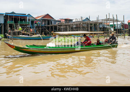 Drei Kambodscha asiatischen Menschen auf einem kleinen grünen lange Motor Boot durch die talaue der Tonle Sap See. Boot mit Zelt für Schatten Stockfoto