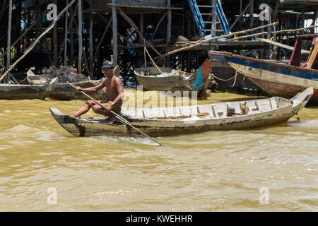 Ein KAMBODSCHANISCHES asiatischen Braun dunkelhäutige Menschen Rudern ein hölzernes Boot in Kampong Phluk Ton Sap See aue Dorf auf Stelzen, in der Nähe von Siem Reap, Kambodscha Stockfoto
