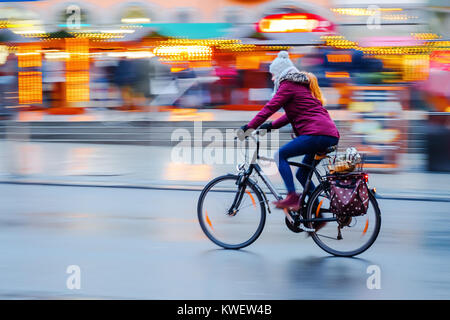 Fotos mit der Kamera gemacht Bewegungsunschärfe, einer Frau, die Fahrten mit dem Fahrrad in die Stadt bei Nacht Stockfoto