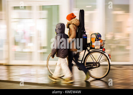 Motion blur Bild einer Frau mit einem Kind, indem Sie ein Fahrrad in der Stadt bei Nacht Stockfoto