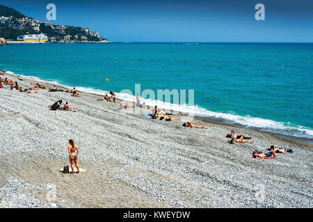 Nizza, Côte d'Azur, Frankreich - 10. Mai 2010: Schöner Strand entlang der Promenade des Anglais in Frankreich mit Menschen Sonnenbaden an einem heißen Sommertag Stockfoto