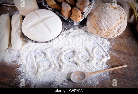 Wort "Brot" auf Mehl auf hölzernen Tisch verstreut geschrieben. Brot, das Zutaten. Von oben Stockfoto