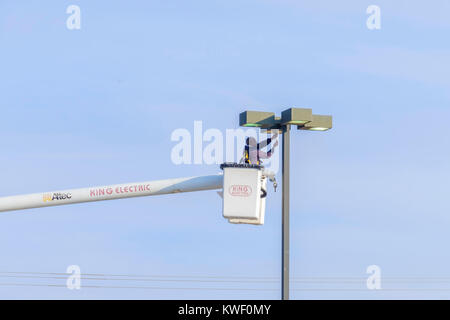 Ein Arbeiter in einem Lift Schaufel arbeitet auf einer Shopping Mall Leuchte. Oklahoma City, Oklahoma, USA. Stockfoto