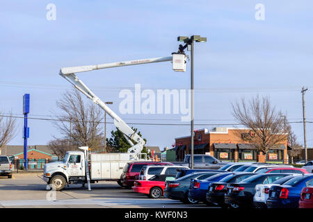 Ein Arbeiter in einem Lift Schaufel arbeitet auf einer Shopping Mall Leuchte. Oklahoma City, Oklahoma, USA. Stockfoto