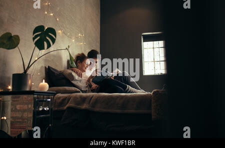 Mann und Frau lesen Buch zusammen auf dem Bett. Gemütliche paar entspannende im Schlafzimmer und Lesen Buch. Stockfoto