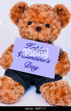 Cute teddy bear Holding ein violettes Schild mit der Aufschrift Jesus liebt Dich auf weißem Hintergrund Stockfoto