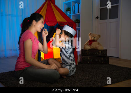Fröhlich lächelnde Mutter mit Bart dress up mit Tochter und kleine Mädchen sailor mit Fernglas an zu spielen. Stockfoto
