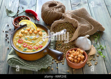 Würzige Linsensuppe mit Chili, Knoblauch und Zwiebel, serviert mit Chili, Zitrone, Croutons und Thymian in der Keramik Keramik Schüssel auf den Tisch, mit Stockfoto
