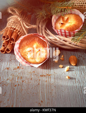 Lemon mini Muffins mit Blumenschmuck in rot-weißem Papier auf rustikalen Holztisch mit Weihnachten Zweige, Mandeln und Zimtstangen. Bild gefiltert. Stockfoto