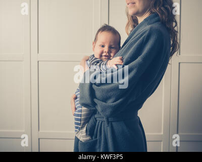 Eine junge Mutter im Bademantel hält Ihr Baby Stockfoto