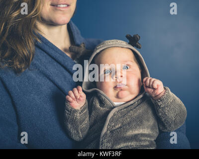 Die junge Mutter hält Ihr Baby tragen ein Rentier Kostüm Stockfoto