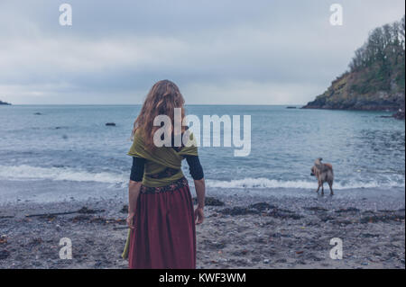 Eine junge Frau geht mit ihrem Hund am Strand