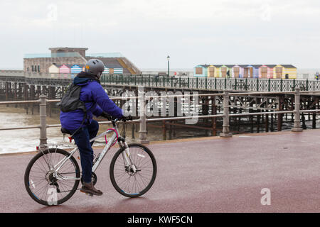 Ein Mann auf einem Fahrrad vorbei an der Pier von Hastings, East Sussex Stockfoto