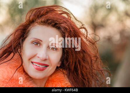 Nahaufnahme von einem schönen Lächeln reife Frau tragen orange Pelz Kragen Stockfoto