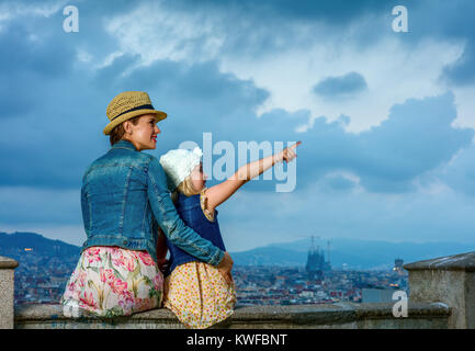 Perfekter Abend mit atemberaubenden Blick. Happy Elegant Mutter und Tochter Reisenden vor Ort Panorama von Barcelona, Spanien zeigt auf etwas Stockfoto