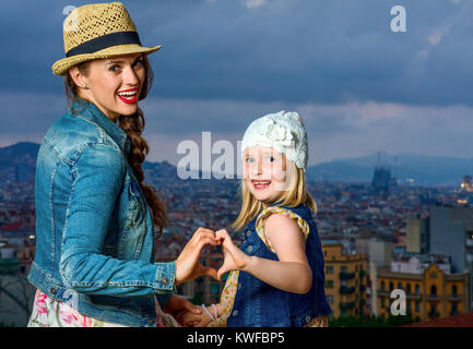 Perfekte Abend mit herrlichen Blick. Portrait von eleganten Mutter und Kind Reisende in der Vorderseite des Stadtbild von Barcelona, Spanien, herzförmige Stockfoto