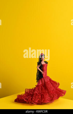 Ein typisch spanisches Puppe gekleidet wie ein Flamenco Tänzerin, mit dem charakteristischen traje de flamenca, die typischen dot-gemusterten Kleid, in einem gelben backgroun Stockfoto