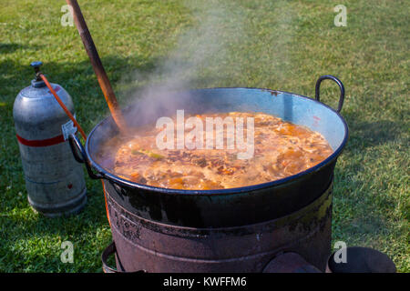 Vorbereiten von traditionellen ukrainischen Suppe Borschtsch in einem großen Topf Kessel auf Gas Lagerfeuer im Freien Stockfoto