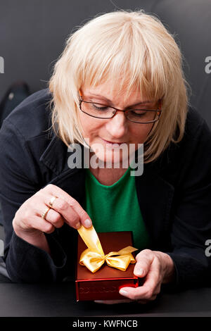 Attraktive reife Frau mit einem Geschenk Box und glücklich lächelnd Stockfoto