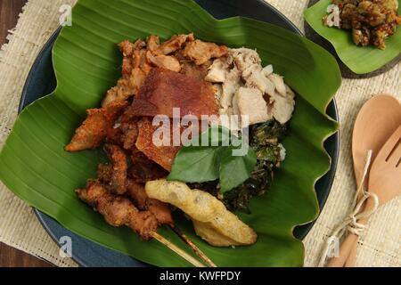 Nasi Campur babi guling. Balinesen Reis Reisgericht mit gedämpftem Reis garniert mit verschiedenen Gerichte der traditionellen Schweinebraten. Stockfoto